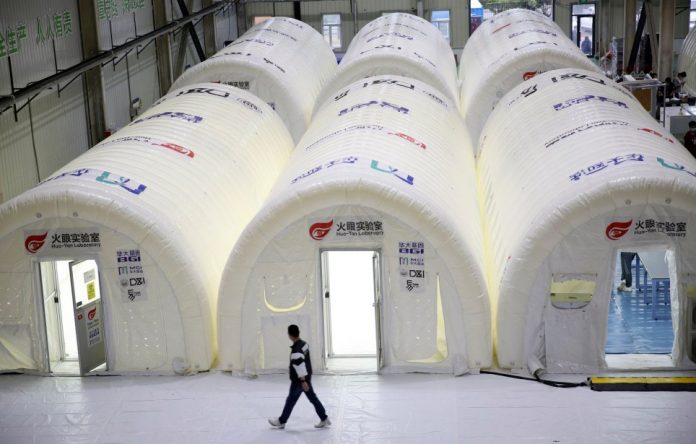 A man walks past temporary COVID-19 test processing labs set up inside inflatable tents in Qingdao in eastern China's Shandong Province, Wednesday, Oct. 14, 2020. China says it has carried out more than 4.2 million tests in the northern port city of Qingdao, with no new cases of coronavirus found among the almost 2 million sets of results received. (Chinatopix via AP)