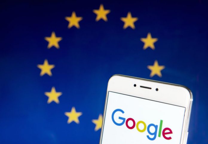 Google logo on phone screen, with EU flag as backdrop