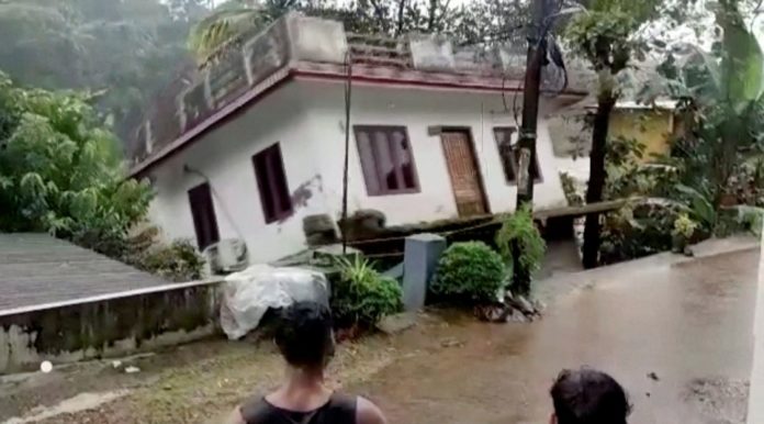 People watch a house being washed away in river due to strong current after heavy rains at Kottayam in Kerala, India, October 17, 2021.