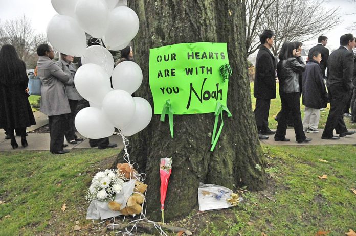 On December 12, 2012, a green poster on a tree memorializes Noah Pozner, a 6-year-old killed in the Sandy Hook school shooting.