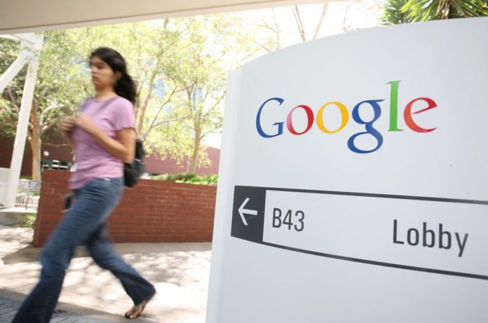 A woman walks past a Google sign at company offices.