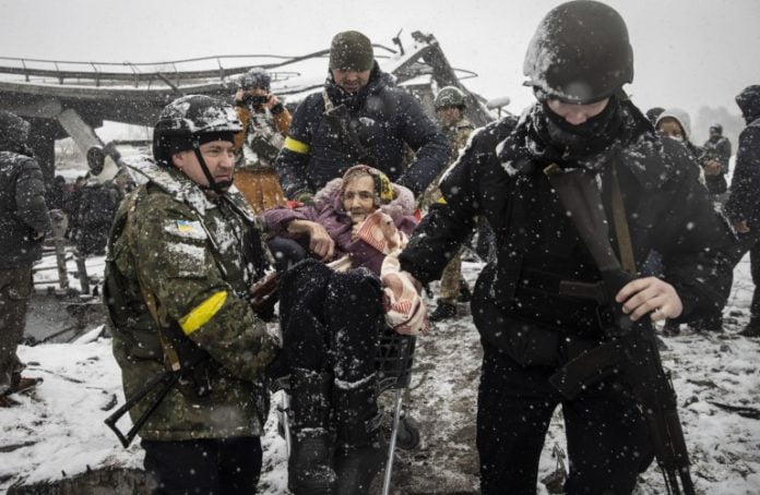 IRPIN, UKRAINE - MARCH 08: Officers evacuate an elderly woman as civilians continue to flee from Irpin due to ongoing Russian attacks as snow falls in Irpin, Ukraine on March 08, 2022. (Photo by Emin Sansar/Anadolu Agency via Getty Images)