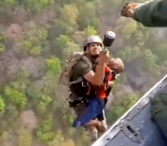 A rescuer carries a child to a helicopter during a rescue operation after mid-air collision of two cable cars on Sunday trapped nearly 50 people in a dozen cars, in Deoghar district, Jharkhand state, India in this still image taken from a handout video obtained April 12, 2022. Courtesy Indian Air Force/Handout via REUTERS THIS IMAGE HAS BEEN SUPPLIED BY A THIRD PARTY. MANDATORY CREDIT