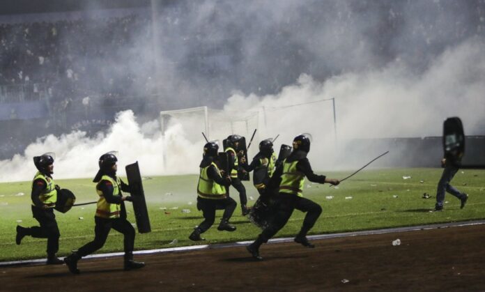 epa10218885 Police officers runs as they try to stop soccer fans from entering the pitch during a clash between fans at Kanjuruhan Stadium in Malang, East Java, Indonesia 02 October 2022. At least 127 people including police officers were killed mostly in stampedes after a clash between fans of two Indonesian soccer teams, according to the police. EPA/H. PRABOWO