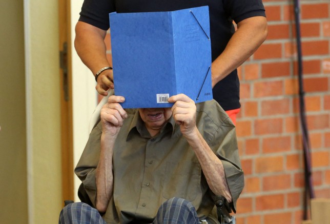 Former Nazi concentration camp guard Josef Schuetz hides his face behind a folder as he arrives on June 28, 2022 at a gym used as a makeshift courtroom in Brandenburg an der Havel, eastern Germany, where his verdict was spoken. - The court gave its verdict in the trial of the 101-year-old man, the oldest person so far to be charged with complicity in war crimes during the Holocaust. Josef Schuetz, accused of being complicit in the murder of 3,518 Soviet prisoners of war at the concentration camp Sachsenhausen during World War II, was sentenced to five years in prison. (Photo by Adam BERRY / AFP) (Photo by ADAM BERRY/AFP via Getty Images)