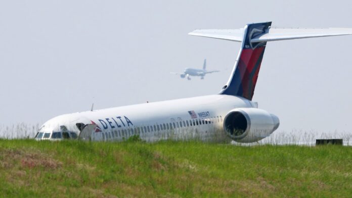 Delta passengers exit their flight using the jet slide after the plane lands without gear extended